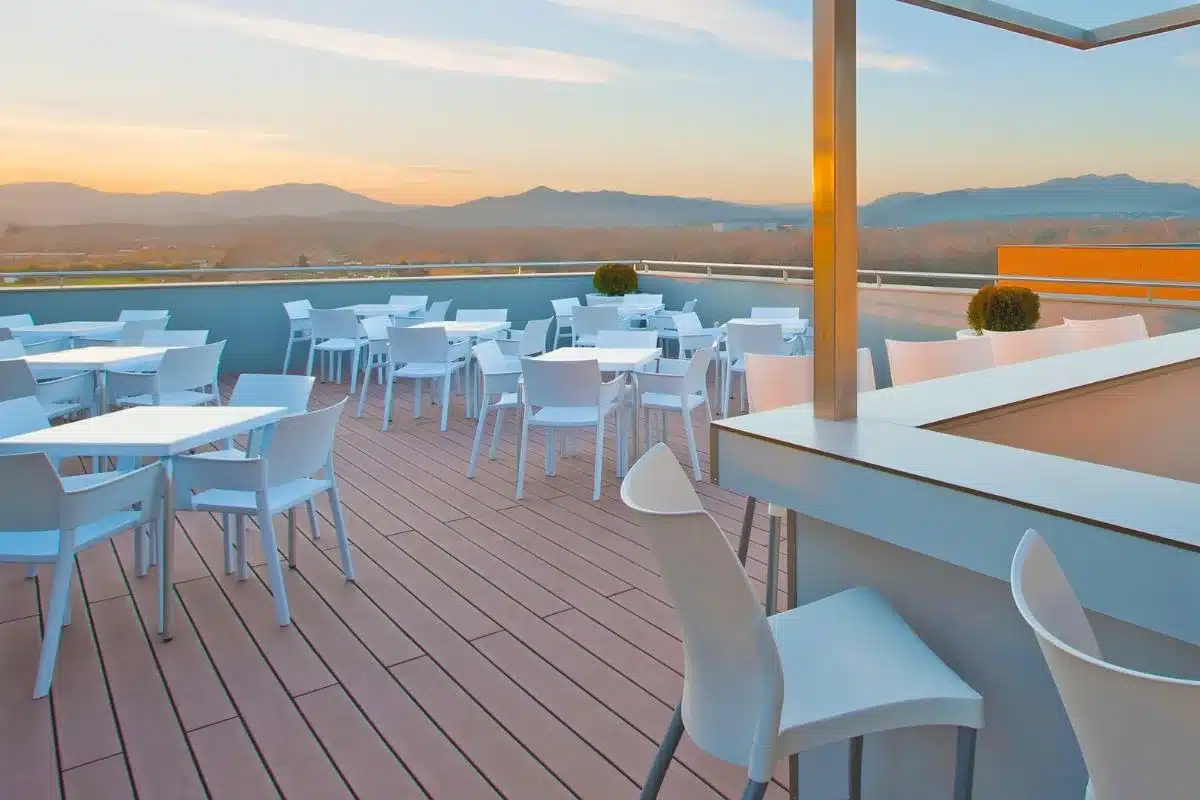 Terraza urbana con mobiliario blanco y suelo de madera tecnológica