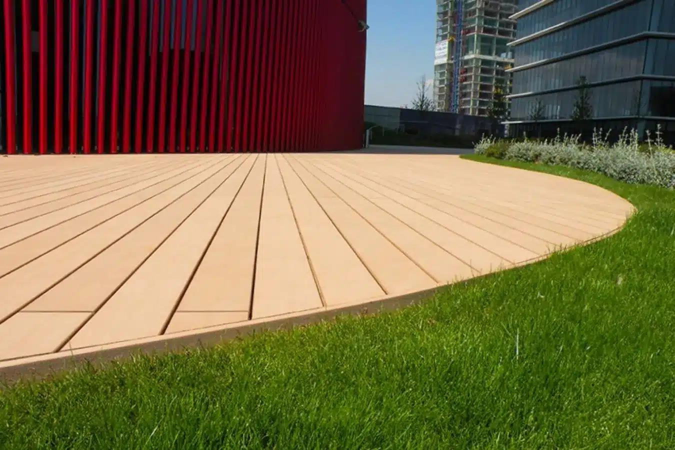 Tarima exterior VISENDUM combinada con césped artificial en zona ajardinada urbana