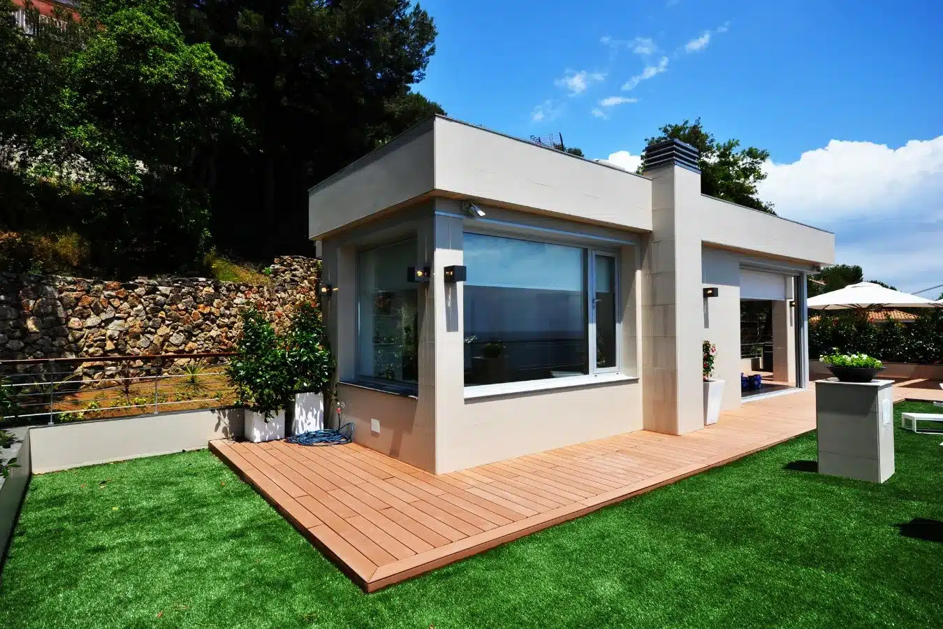 Tarima exterior VISENDUM frente a vivienda unifamiliar con césped artificial