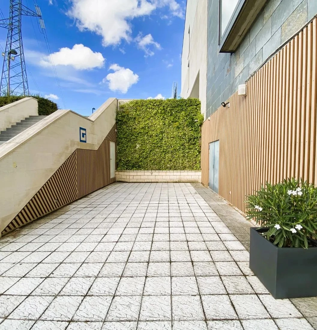 Pasillo exterior con madera tecnológica VISENDUM® y jardín vertical decorativo
